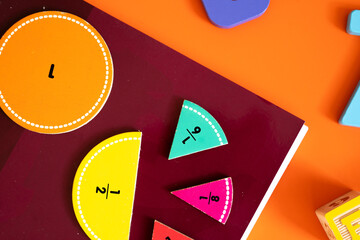 Brightly colored wooden numbers are scattered across an orange surface. The playful digits in yellow, blue, red, green, and light blue evoke fun learning and early math