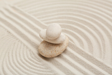 Beautiful composition with spa stones and lines on sand as background, closeup. Zen concept