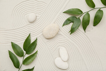 Spa stones and green leaves on sand as background, closeup. Zen concept
