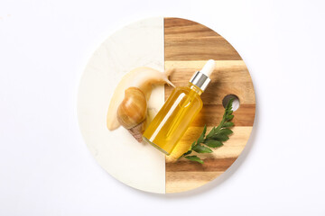 Tray, giant Achatina snail and bottle of cosmetic product on white background, closeup