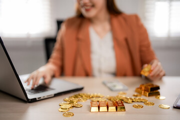 Adult Asian businesswoman trades gold bullion coins laptop manages investments digital finance...