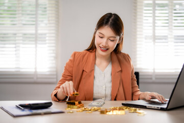 Asian woman investor manages gold assets portfolio strategizing financial growth at home office desk builds wealth future precious metals trading investment