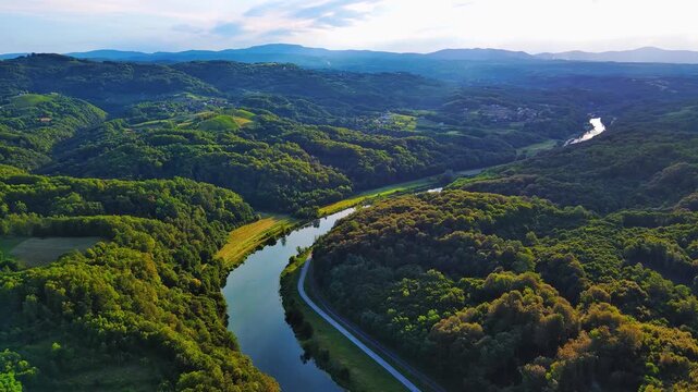 River Kupa next to the highway between dense forests in the sunlight
