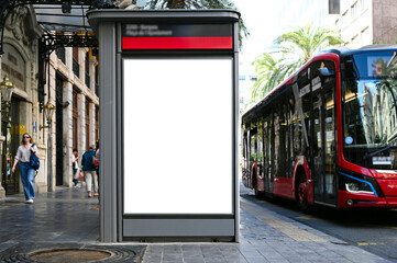bus shelter with vertical blank ad panel. billboard display. empty white lightbox sign at bus stop. mockup base. city transit station. urban street. park setting with palm trees. outdoor advertising