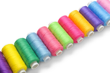 Row of colorful thread spools on white background