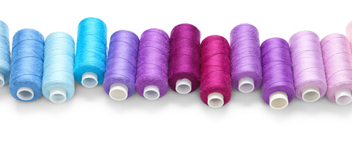 Row of colorful thread spools on white background