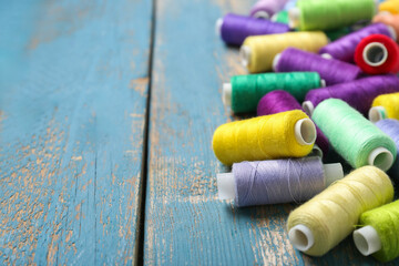 Colorful thread spools on blue wooden background