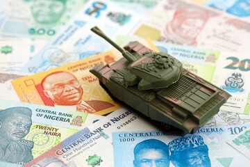 Nigerian naira currency money bills and toy tank close up. The concept of army funds and weapons...