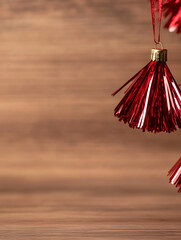 Festive red tinsel ornament hanging against a warm wooden backdrop, evoking holiday cheer and cozy winter vibes. Add a touch of sparkle to your seasonal projects!