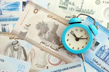 United Arab Emirates dirham currency money bills and alarm clock close up. The concept of time...
