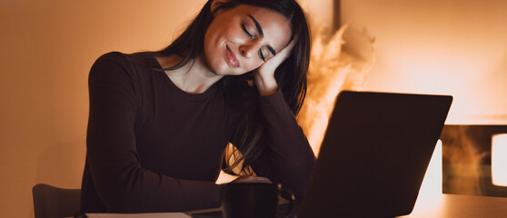 Tired woman massaging temples, suffering from headache after computer work, sitting at desk with laptop at home, exhausted young female with closed eyes touching head, relieving pain, migraine