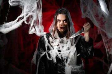 sinister gothic woman killer, vampire with creepy makeup and knife, trapped spider web. Fantasy...