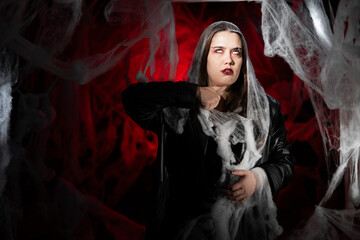 gothic woman with creepy vampire makeup trapped in spider web trying to scare. Fantasy scary girl...