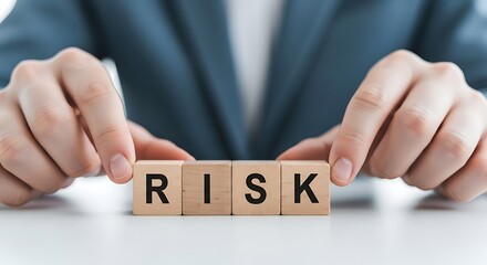 Hands arranging wooden blocks with the word risk on a white surface, representing business challenges and strategy