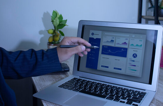 Businessman reviewing a business intelligence (BI) dashboard on a laptop. Concept of data analysis, performance tracking, and modern dark mode user interface (UI).