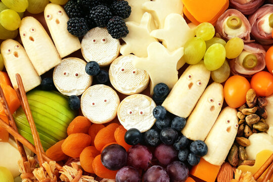 Healthy Halloween fun food mix: cheese ghosts and mummies, banana ghosts and grapes, blueberries and blackberries. Party spooky snacks for kids