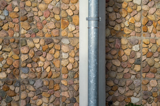 Stone pebble wall and metal drainpipe texture