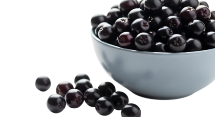 A light blue bowl filled with ripe black olives and some scattered on a black surface isolated on transparent background