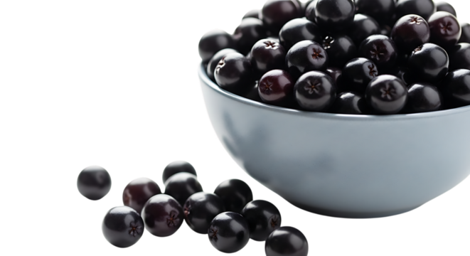A light blue bowl filled with ripe black olives and some scattered on a black surface isolated on transparent background