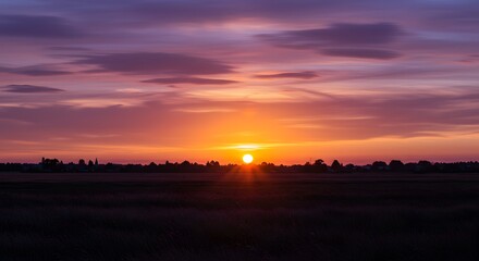 Vibrant Sunset Over Rural Landscape with Silhouetted Trees and Horizon Line