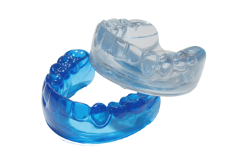 Two dental mouthguards, one clear and one blue, overlap