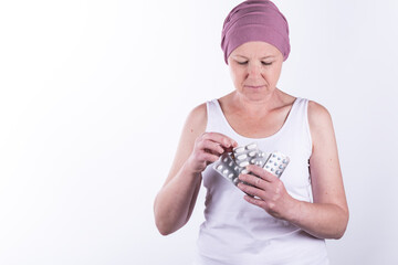Woman undergoing cancer treatment who needs to take pills as part of her therapy. She holds them in her hand, fanned out, to show the different medications.