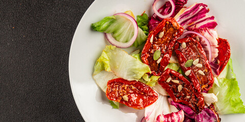 Salad sun-dried tomato green leaf lettuce, onion natural product tasty snack fresh delicious gourmet food background on the table rustic top view copy space keto and paleo diet vegan and vegan food