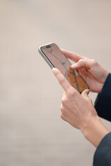 Fototapeta premium Vertical close-up of female hands holding smartphone with navigation map on screen. Concept of gps navigation, travel route, and mobile technology.