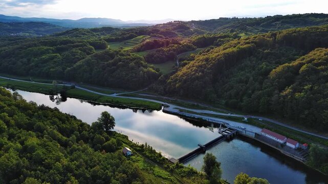 The Kupa river with a hydroelectric power plant near the road in a dense green forest
