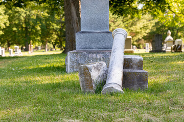 Graveyard headstone broken and damaged. Cemetery maintenance, grave vandalism, and perpetual care concept.