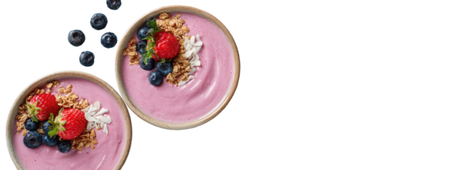 Two bowls of vibrant pink smoothie bowls topped with blueberries, raspberries, granola, and coconut