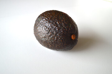 Ripe Hass avocado with dark textured skin on white background - fresh organic fruit