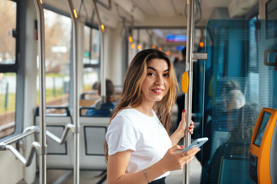Young Woman Enjoying Her Ride on Public Transport While Using Her Smartphone in a Busy City During the Day - Powered by Adobe