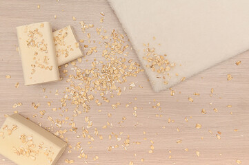 White towel, white soap, oatmeal on wooden background.