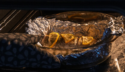 Baked in the oven in foil with spices, herbs and lemon in a baking dish, top view. Fresh baked walleye fish in foil for baking with vegetables, lemon and spices close-up. Pike-perch baked in foil. 