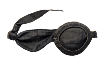 Dark, worn eye-covering, fabric straps tied