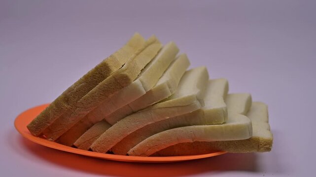 This video features a loaf of sliced white bread ​​falling to the side, presented in a professional product videography style. The bread appears fresh.