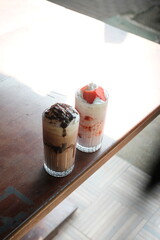 Enjoy delicious chocolate and strawberry milkshakes served on a wooden table, perfect for a refreshing treat on a sunny day