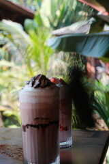 Indulge in refreshing chocolate strawberry smoothies with lush greenery backdrop, perfect for summer vibes and healthy lifestyle promotions