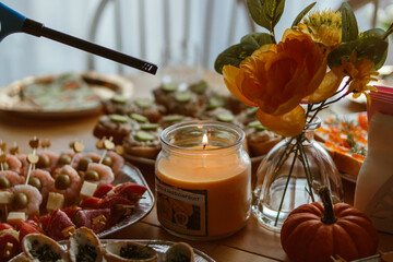 Table with appetizers and candle being lit, artificial flowers centerpiece