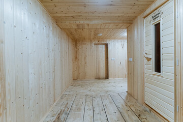 woodpaneled changing area with open sauna door, timber floor and soft ceiling light create...