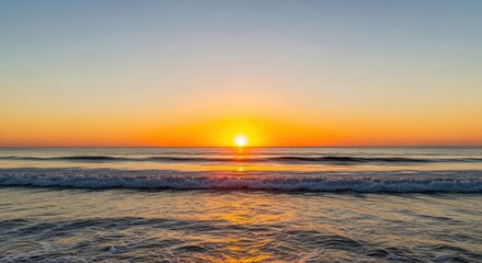 Obraz premium Sunset over ocean waves with vibrant orange sky