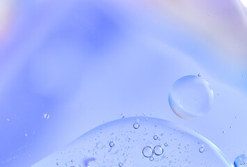Violet blue pastel background with a drop of oil and a bubble, minimalistic and dreamy. Macro photography, smooth transitions, includes space for text.