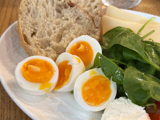 Halved eggs with soft yolk placed beside bread and fresh spinach. Homemade meal expressing comfort, taste, and natural simplicity.