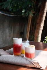 Enjoy colorful handcrafted cocktails with delightful layered flavors in a serene outdoor setting, perfect for summer refreshment and trendy lifestyle vibes