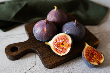 Fresh ripe figs on rustic wooden cutting board, whole and halved fruits.