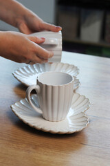 Woman reviewing porcelain tea mugs and matching heart-shaped saucers. A set of tea cups. Heart-shaped saucers.
