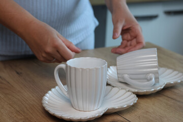 Woman reviewing porcelain tea mugs and matching heart-shaped saucers. A set of tea cups. Heart-shaped saucers. Horizontal shot.