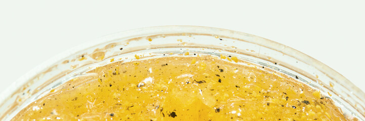 Close-up of lemon gel with black pepper in a transparent glass container.