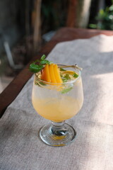 Refreshing peach cocktail with mint garnish on linen surface invites a taste of summer, perfect for menus, blogs, and social media marketing